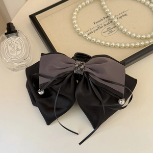 Detail of satin bow hair claw clip with rhinestones and pearl tassels on a vanity table