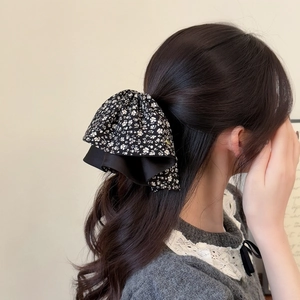 Detail view of large black and white floral bow hair claw clip with satin ruffle edges