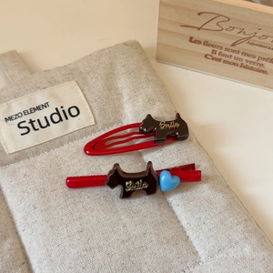 Dettaglio di fermagli per capelli rossi con design a cucciolo ed elemento cuore blu