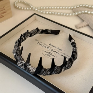 Close-up of gothic punk headband with black spikes and grey plaid fabric texture