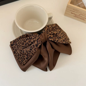 Dettaglio di un elegante fiocco per capelli a doppio strato con stampa leopardata e raso