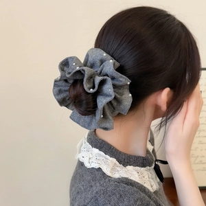 Elegant grey knitted scrunchie with white pearls on a stylish bun hairstyle