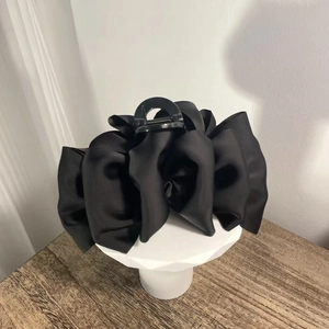 Elegant large black satin puff pleated hair claw clip displayed on a white stand