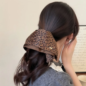 Detail shot of a large leopard print bow hair clip worn on a low ponytail hair style