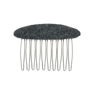 Dettaglio macro della trama in feltro grigio scuro su un pettine per capelli in metallo