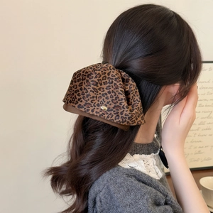 Elegant leopard print bow hair clip for women with a gold logo detail on a high ponytail