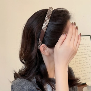 Brown plaid fabric headband with a stylish preppy pattern worn on long curly hair