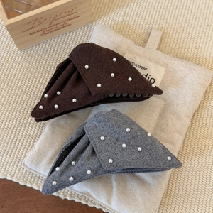 Close-up of elegant triangular hair claws with faux pearls and felt fabric texture