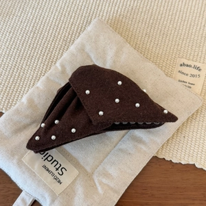 Detail view of a brown triangular pearl hair claw clip with cozy felt fabric texture