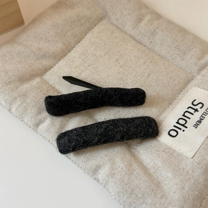 Elegant pair of black felt wool hair clips with a minimalist textured fabric finish