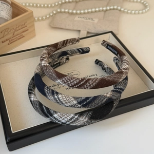 Detailed view of three handmade plaid headbands in diverse patterns on a tray