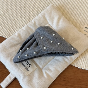 Detail of grey felt hair claw clip with white pearls on a minimalist linen background