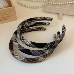 Close-up of handmade plaid fabric headbands with woven labels on vintage background