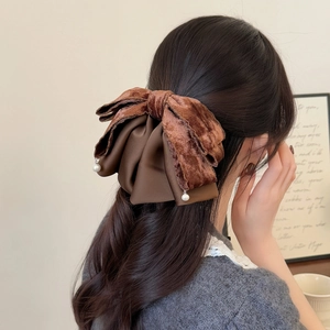 Brown velvet and satin bow hair claw clip with pearl pendants shown on a model