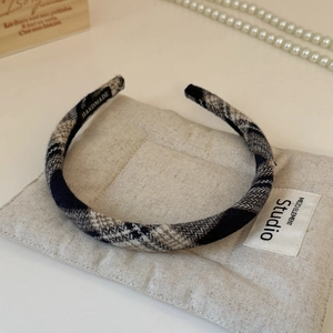 Detail of a plaid fabric headband featuring a handmade label and elegant pearl decor