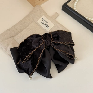 Detail view of black velvet bow hair claw clip with white pearl accents and wave stitching