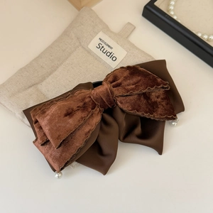 Detailed close-up of a vintage brown velvet bow hair claw clip with delicate pearl accents
