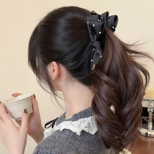 Elegant black polka dot bow banana clip hair accessory styled on a wavy ponytail