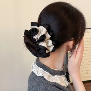 Detailed view of the contrast color satin scrunchie styled on a messy hair bun
