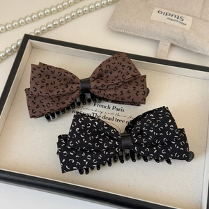 Detail view of vintage leopard print bow banana clips on an elegant jewelry tray