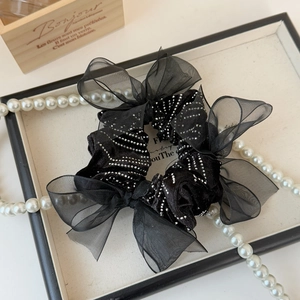 Detail of black satin organza scrunchie with sparkling sequins and bow ribbon design
