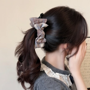 Elegant bow hair clip with vintage brown plaid pattern worn on a ponytail