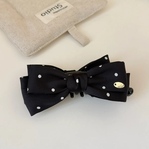Detailed view of polka dot chiffon bow banana clip with elegant gold logo emblem