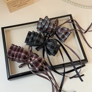 Three-piece vintage plaid bow banana clips with long ribbons on a decorative display tray
