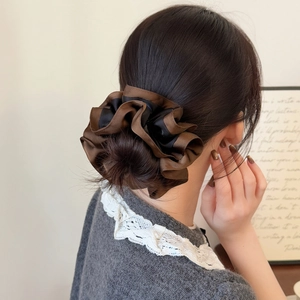Elegant two-tone satin scrunchie in brown and black worn on a stylish high bun