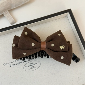 Detail of coffee brown polka dot bow hair clip with a gold handmade heart charm