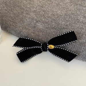 Detail of black velvet bow hair clip with white polka dot edges and gold metal buckle