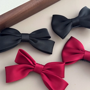 Detailed view of elegant burgundy and black satin bow hair clips in high-density fabric