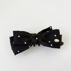 Elegant black polka dot bow hair clip with gold metal emblem for women hair styling