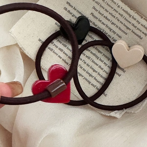 Détail de pendentifs en forme de cœur rouge, noir et beige sur des élastiques à cheveux