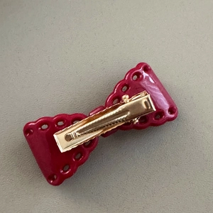 Detailed back view of a dark red bow hair clip featuring a golden metal alligator clip