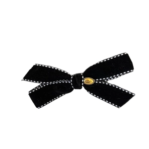 Elegant black velvet bow hair clip with white dotted stitching and gold logo plate
