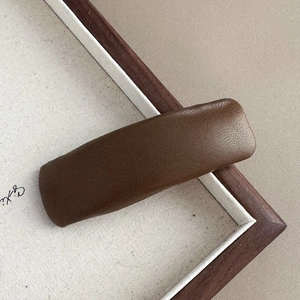 Detail of minimalist dark brown leather hair clip with lychee texture for autumn