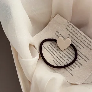 Détail de l'accessoire en forme de cœur sur élastique à cheveux sur fond de lin