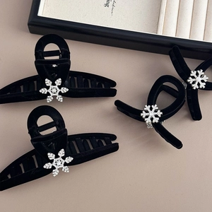Detailed macro view of black velvet hair claws with rhinestone snowflake and pearl accents