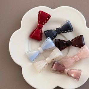 Close-up of bow hair clips in multiple colors with hollow wave edges on a ceramic tray