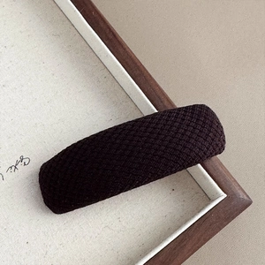 Close-up of deep brown plaid hair clip with textured fabric on a wooden background