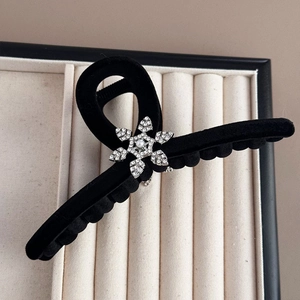 Close-up of black velvet hair claw clip with rhinestone snowflake and center pearl detail