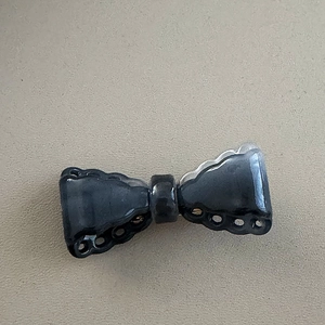 Detail view of a vintage black bow hair clip featuring intricate hollowed-out lace edges