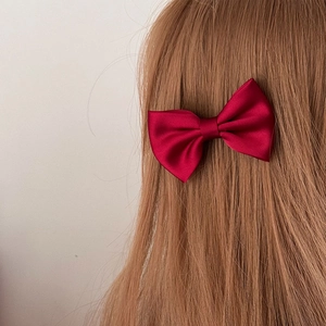 Elegant wine red satin bow hair clip for women styled on long brown hair in side view