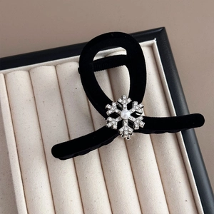 Detail of black velvet hair claw clip featuring a rhinestone snowflake with central pearl inlay