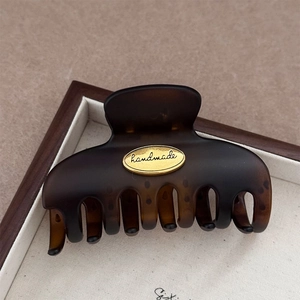 Detail of tortoise shell claw clip with golden handmade metal plate on a wooden tray