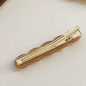Detail view of golden metal alligator hair clip with amber resin and anti-slip teeth