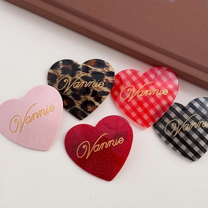 Set of heart-shaped acetate hair clips in leopard, pink, and plaid patterns with gold text