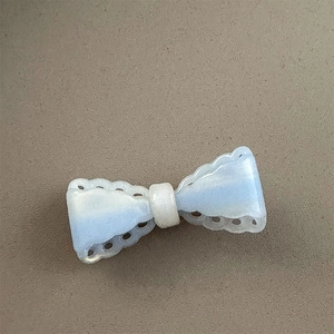 Close-up of a light blue pearlescent bow hair clip with decorative hollowed edges