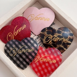 Detail showing acetate heart hair clips in pink, leopard, and plaid with Vannie lettering